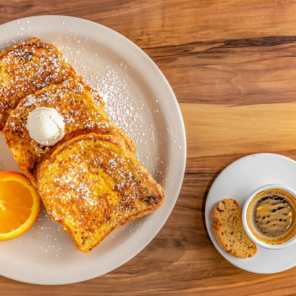Buttermilk Eatery's French toast with powdered sugar, butter, orange slice, and coffee with biscotti.