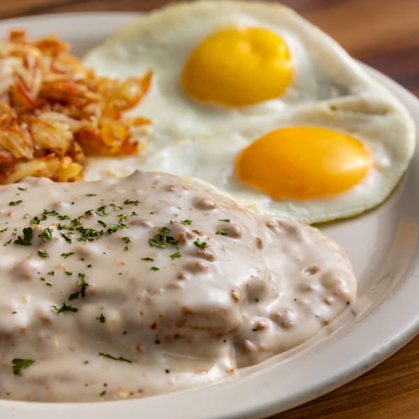 Buttermilk Eatery's breakfast plate with biscuits and gravy, hash browns, and two fried eggs.