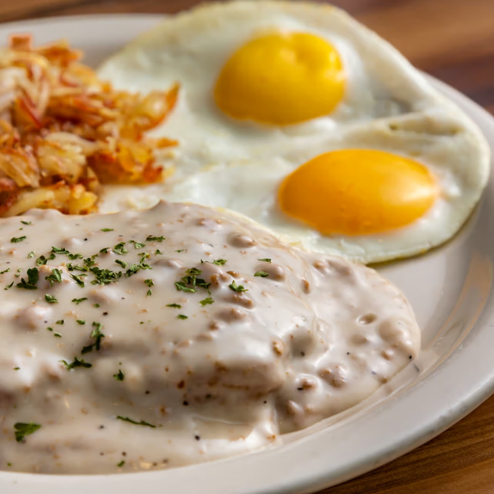Buttermilk Eatery's breakfast plate with biscuits and gravy, hash browns, and two fried eggs.