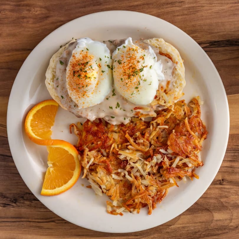 Buttermilk Eatery's biscuits and gravy with poached eggs, hash browns, and orange slices.