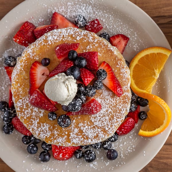 Buttermilk Eatery's pancake topped with strawberries, blueberries, whipped cream, powdered sugar, and orange slices.
