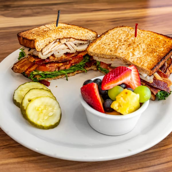 Buttermilk Eatery's turkey club sandwich with bacon, lettuce, tomato, pickles, and a fruit cup.