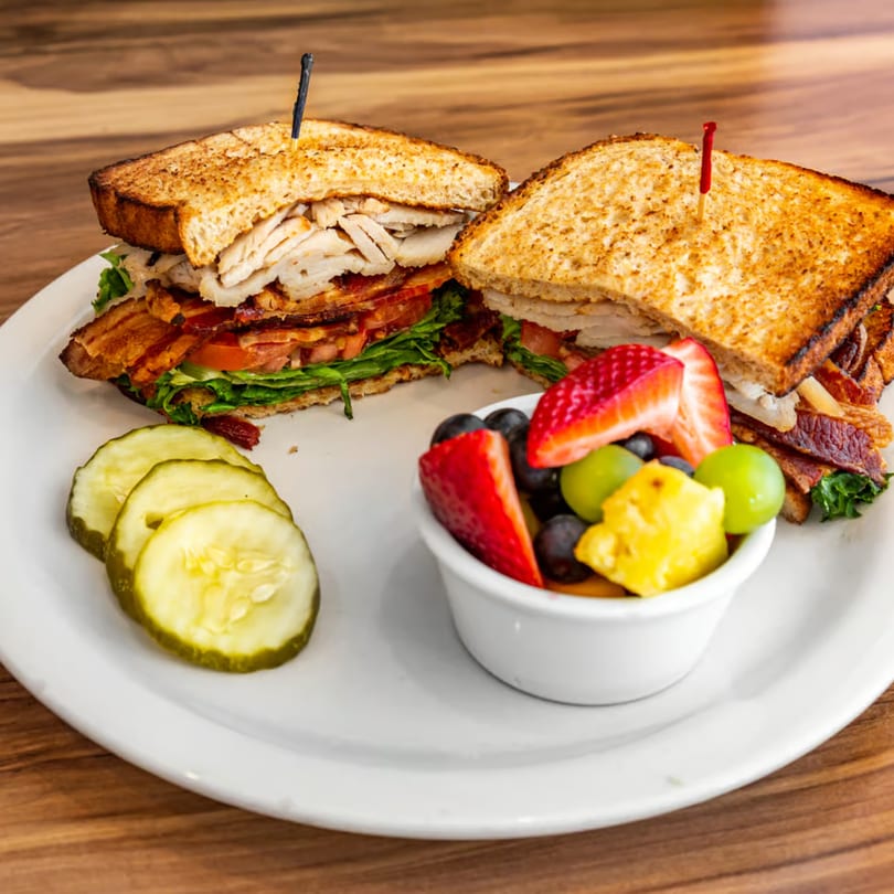 Buttermilk Eatery's turkey club sandwich with bacon, lettuce, tomato, pickles, and a fruit cup.